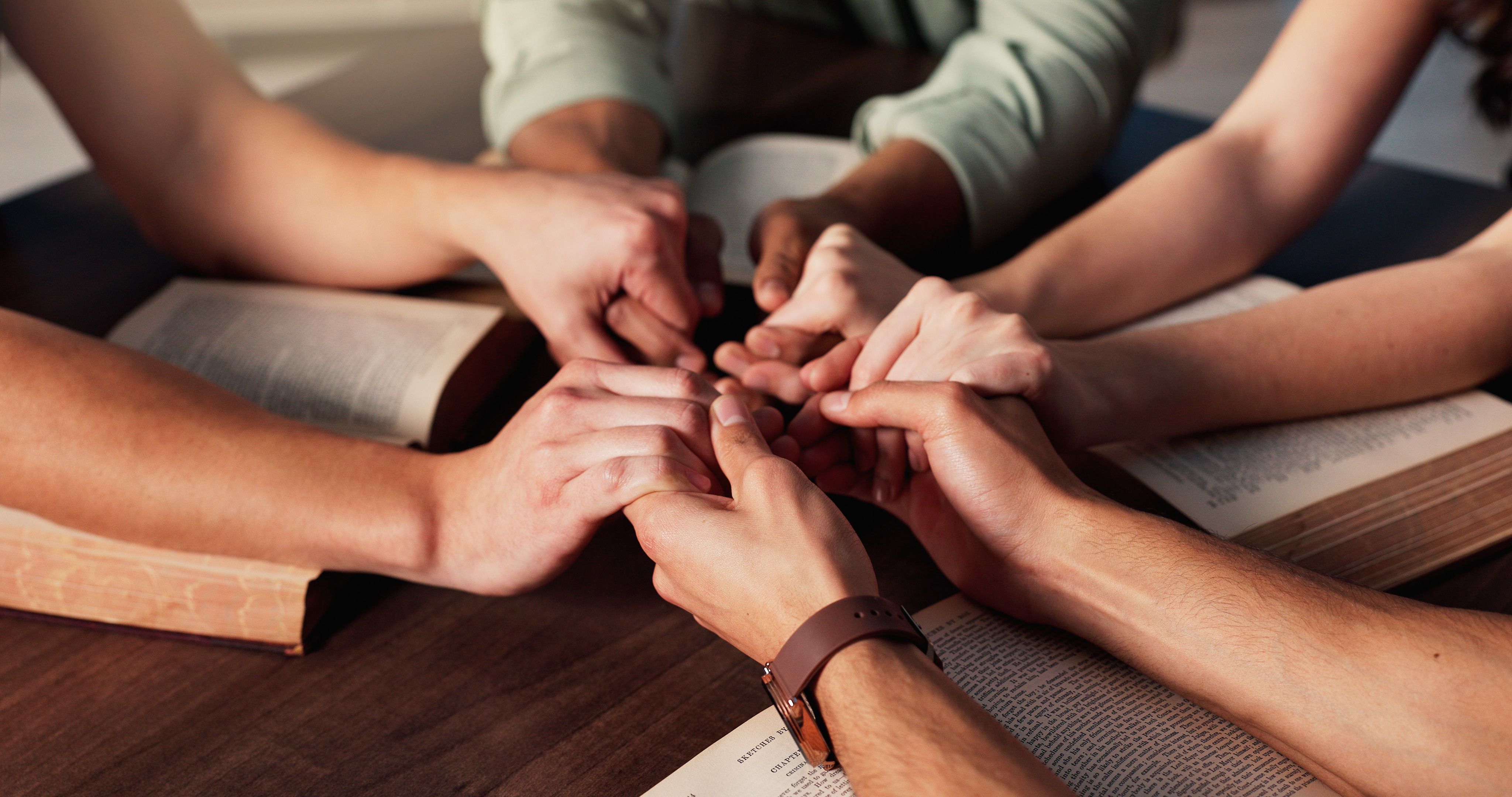 Personas unidas en oración alrededor de Biblias abiertas